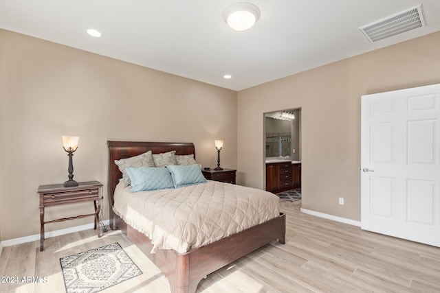 bedroom with ensuite bath and light wood-type flooring