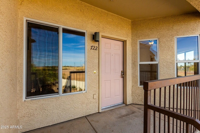 entrance to property featuring a balcony and stucco siding