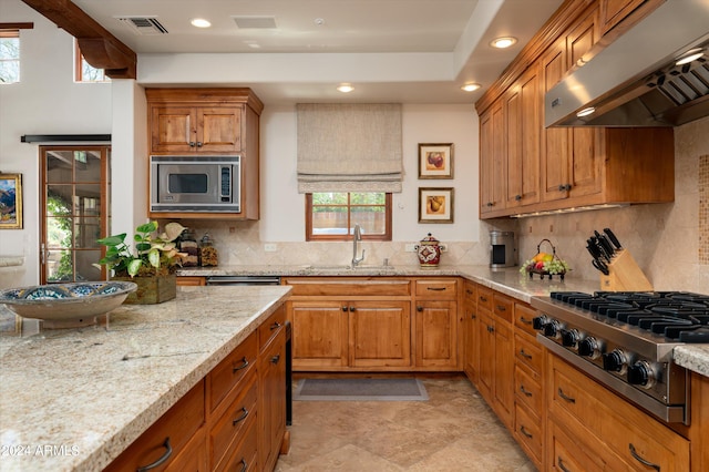 kitchen featuring decorative backsplash, wall chimney exhaust hood, sink, appliances with stainless steel finishes, and light tile patterned floors