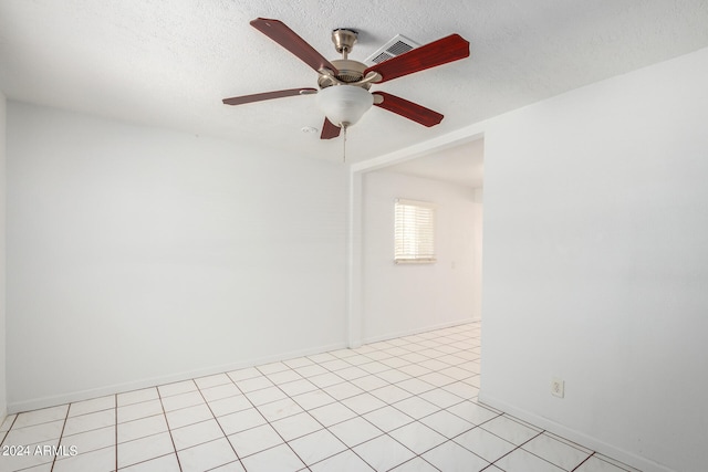 tiled empty room with ceiling fan and a textured ceiling