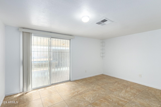 tiled empty room with a textured ceiling