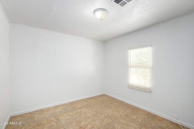 tiled spare room featuring a textured ceiling