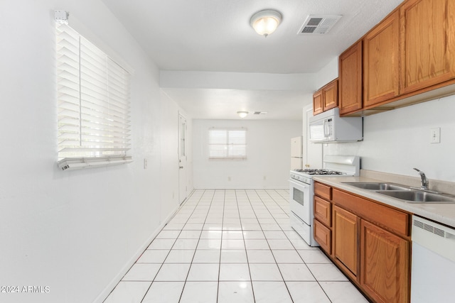 kitchen with light tile patterned floors, sink, and white appliances