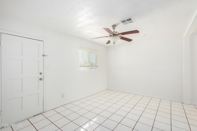 spare room with a textured ceiling, ceiling fan, and light tile patterned flooring