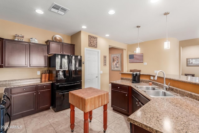 kitchen with dark brown cabinetry, black fridge with ice dispenser, sink, hanging light fixtures, and stove