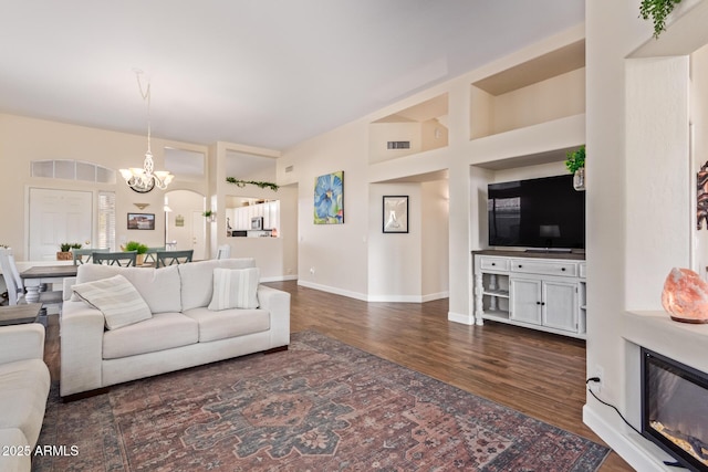 living room with an inviting chandelier, dark hardwood / wood-style floors, and a high ceiling