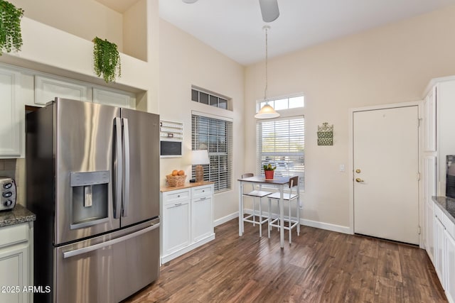 kitchen featuring white cabinetry, dark hardwood / wood-style flooring, stainless steel fridge, and dark stone countertops