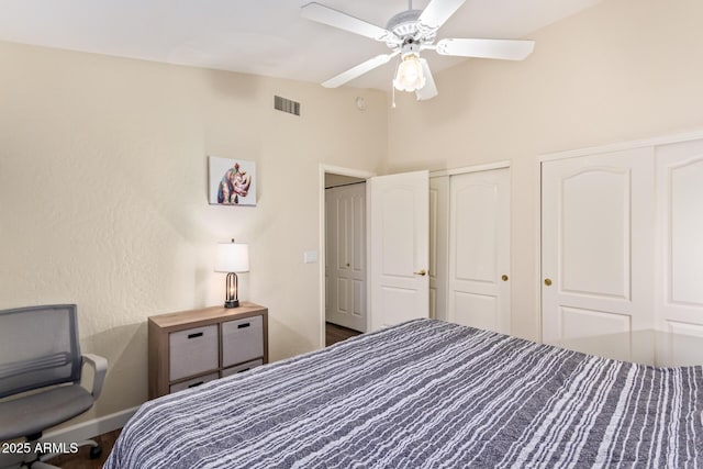 bedroom featuring multiple closets, lofted ceiling, and ceiling fan