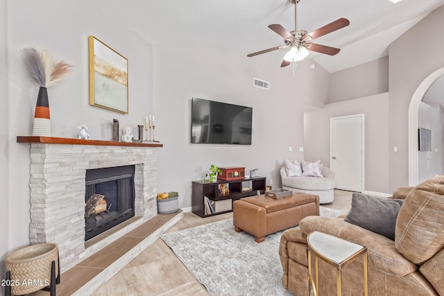 tiled living room with a stone fireplace, high vaulted ceiling, and ceiling fan