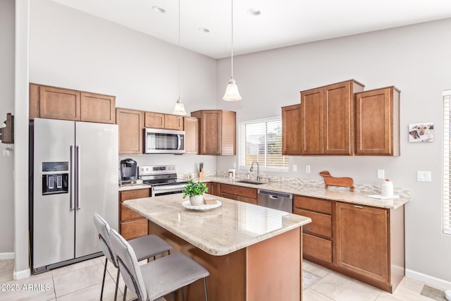 kitchen featuring sink, hanging light fixtures, a kitchen island, stainless steel appliances, and light stone countertops