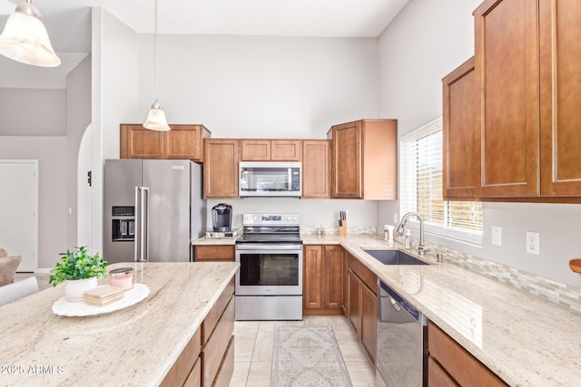 kitchen with appliances with stainless steel finishes, high vaulted ceiling, sink, hanging light fixtures, and light stone counters