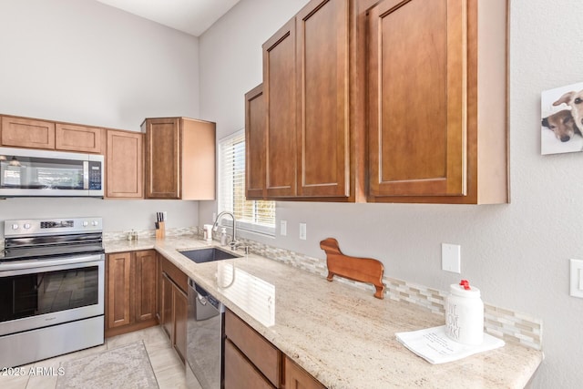 kitchen with appliances with stainless steel finishes, light stone countertops, and sink