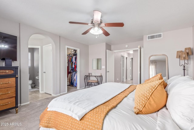 carpeted bedroom featuring a walk in closet, connected bathroom, ceiling fan, and a closet