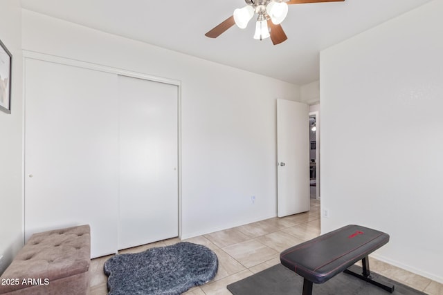 exercise area with ceiling fan and light tile patterned floors