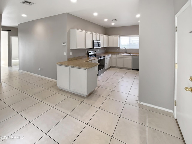 kitchen featuring sink, light tile patterned floors, appliances with stainless steel finishes, white cabinetry, and light stone countertops