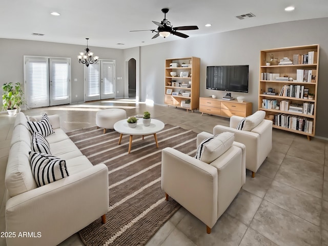 tiled living room featuring ceiling fan with notable chandelier