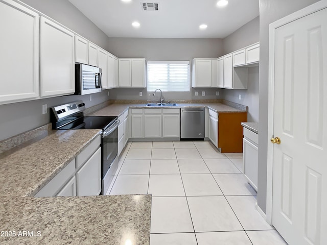 kitchen with sink, light tile patterned floors, white cabinetry, stainless steel appliances, and light stone counters