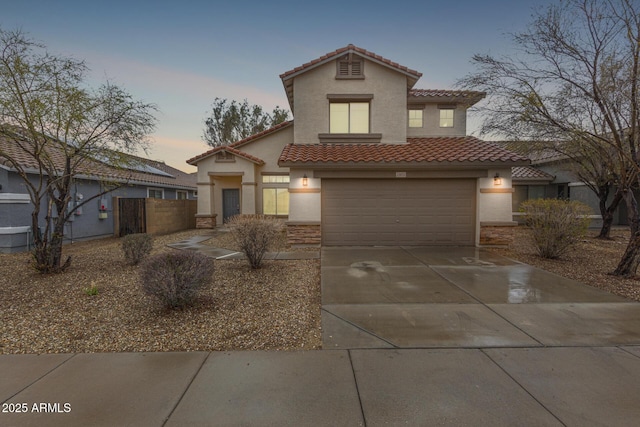 mediterranean / spanish-style house featuring stucco siding, concrete driveway, fence, a garage, and a tiled roof