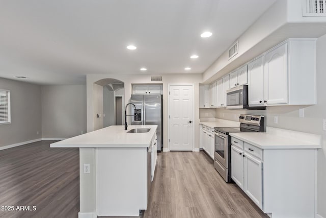 kitchen featuring arched walkways, appliances with stainless steel finishes, light wood finished floors, and visible vents