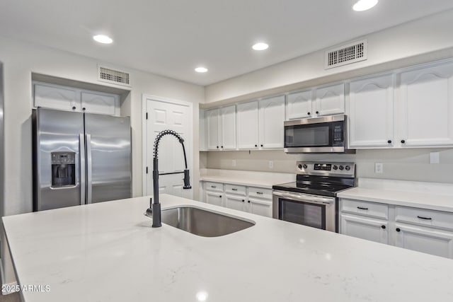 kitchen with visible vents, appliances with stainless steel finishes, white cabinets, and a sink