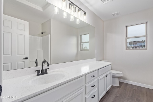 bathroom with visible vents, toilet, vanity, wood finished floors, and walk in shower