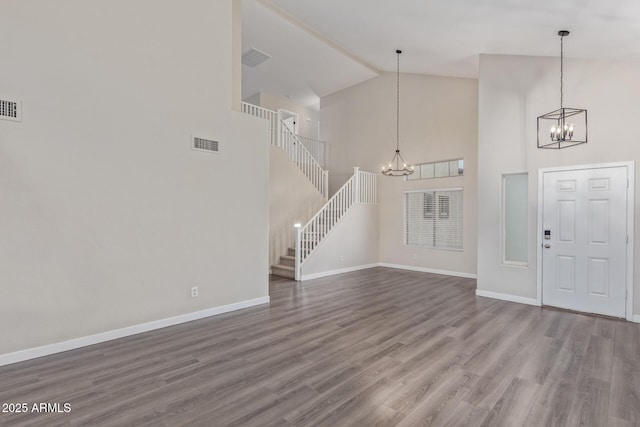 foyer entrance with visible vents, stairway, an inviting chandelier, wood finished floors, and baseboards