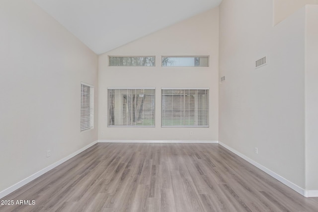 unfurnished living room featuring high vaulted ceiling, baseboards, and wood finished floors