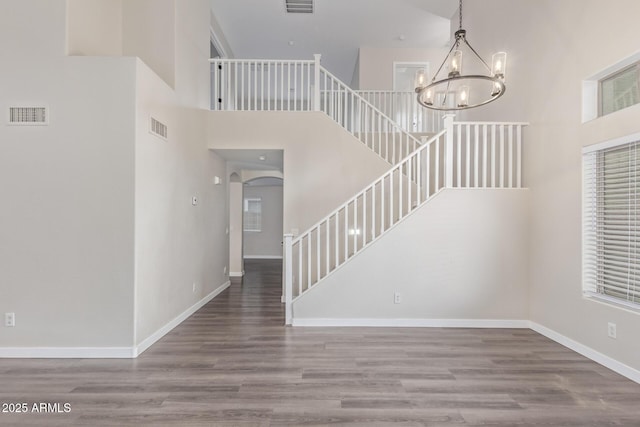 foyer entrance with a chandelier, stairway, wood finished floors, and visible vents