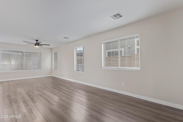 unfurnished room featuring baseboards, visible vents, and wood finished floors