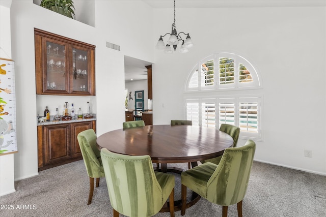 carpeted dining room with an inviting chandelier and high vaulted ceiling