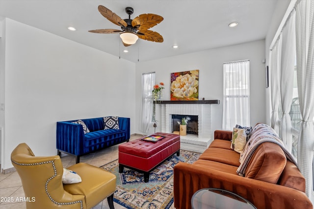 living room featuring light tile patterned floors, a brick fireplace, and ceiling fan