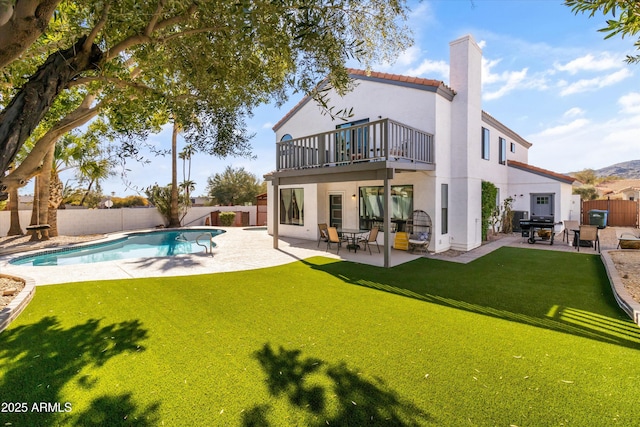 back of property featuring a fenced in pool, a yard, a patio, and a balcony