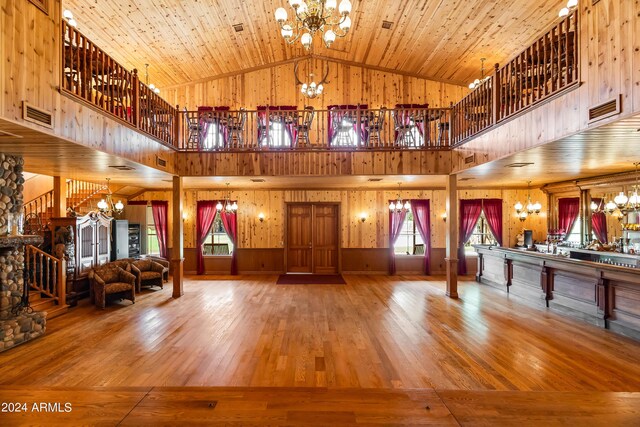 unfurnished living room featuring wooden ceiling, wood walls, hardwood / wood-style flooring, and an inviting chandelier