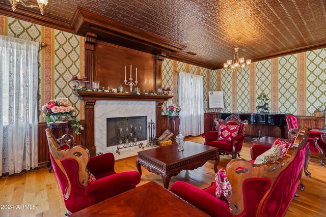 living room with a high end fireplace, a chandelier, a healthy amount of sunlight, and light hardwood / wood-style floors