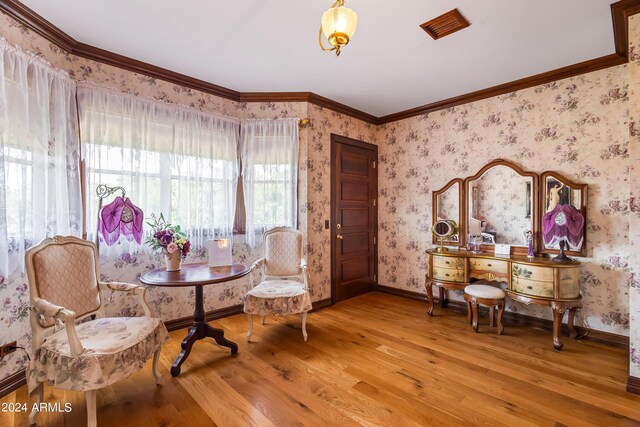 sitting room with ornamental molding and light hardwood / wood-style flooring