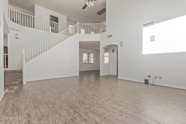 16215 W Durango St, Goodyear, AZ 85338 - unfurnished living room with ceiling fan, wood finished floors, stairway, a high ceiling, and baseboards
