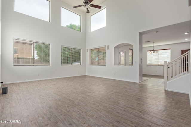 16215 W Durango St, Goodyear, AZ 85338 - unfurnished living room featuring a chandelier, a ceiling fan, wood finished floors, stairs, and a high ceiling