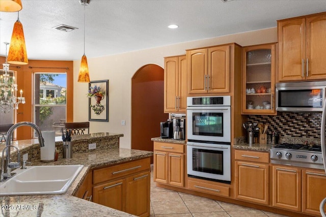5212 S Monte Vista St, Chandler, AZ 85249 - kitchen featuring a sink, stainless steel appliances, arched walkways, decorative backsplash, and pendant lighting