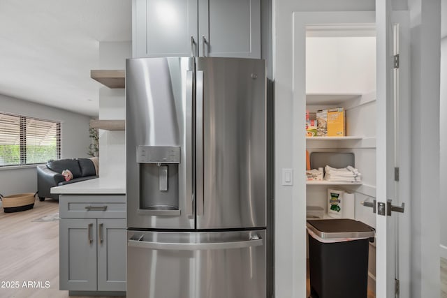 kitchen with stainless steel fridge, open shelves, gray cabinetry, and light wood-type flooring