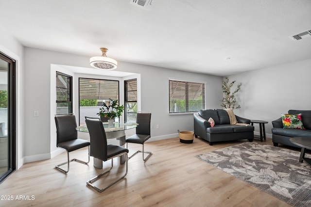 living room featuring visible vents, light wood-style flooring, and baseboards
