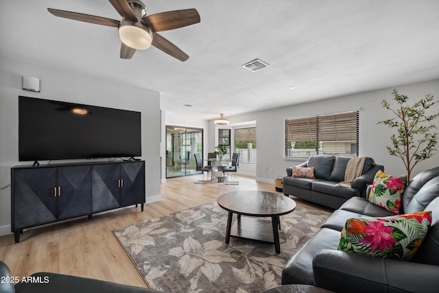 living room with baseboards, a ceiling fan, light wood finished floors, and visible vents