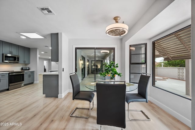 dining space with baseboards, light wood finished floors, and visible vents