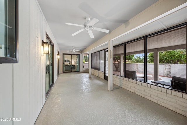 unfurnished sunroom featuring a ceiling fan and a wealth of natural light