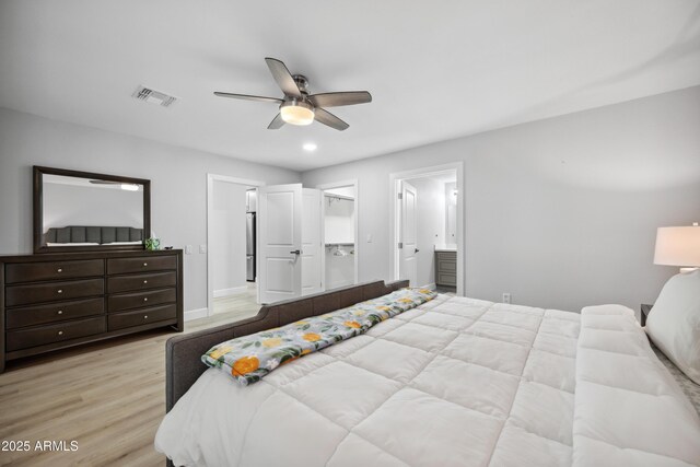 bedroom featuring ceiling fan, visible vents, wood finished floors, baseboards, and ensuite bath