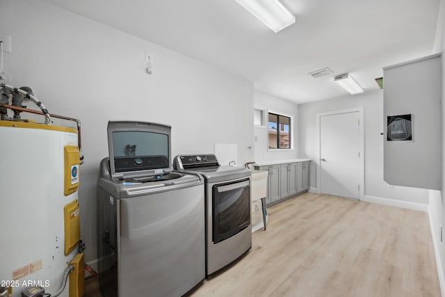 laundry room featuring laundry area, visible vents, secured water heater, light wood-style flooring, and washer and clothes dryer