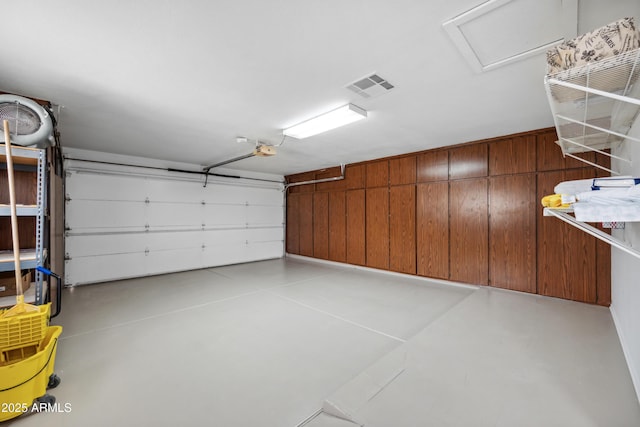garage with visible vents, wood walls, and a garage door opener