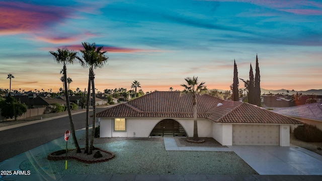 view of front of property with an attached garage, driveway, a tile roof, and stucco siding