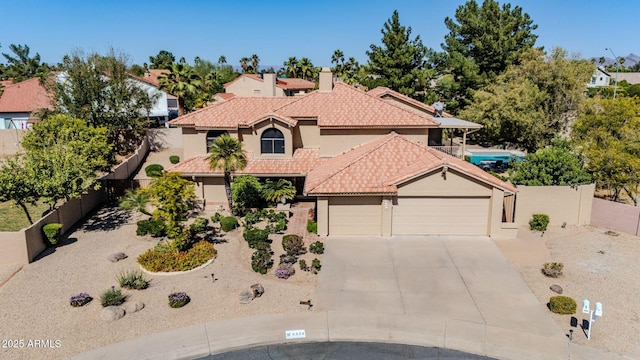 view of front of property with a tiled roof, concrete driveway, stucco siding, a fenced backyard, and an attached garage