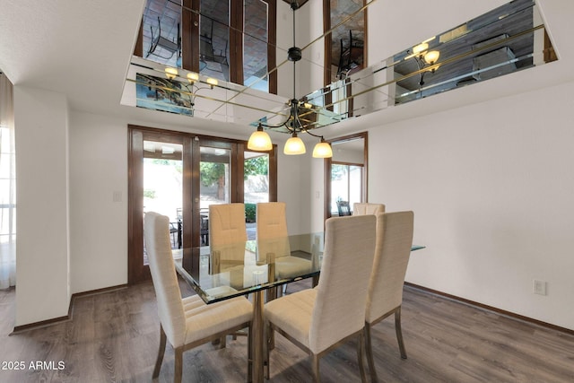 dining area featuring french doors, baseboards, wood finished floors, and a towering ceiling