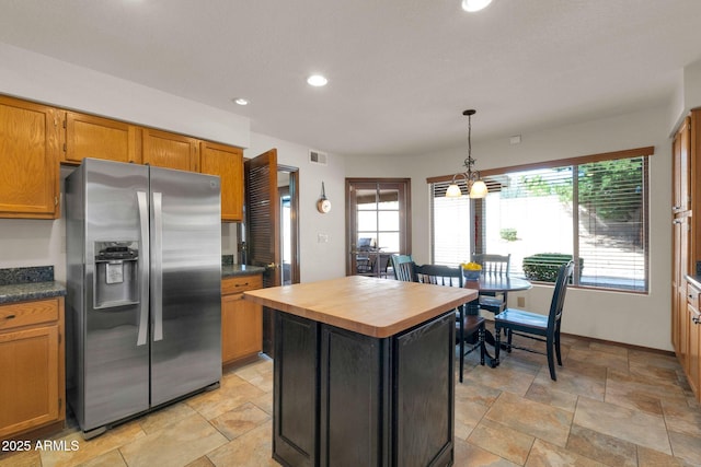 kitchen featuring visible vents, pendant lighting, wood counters, a kitchen island, and stainless steel fridge